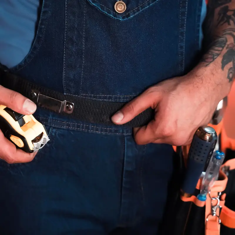 a close-up of double layer skimiski belt, showing the electrician is putting his tape measure on it's holder which is fixed strongly to the adjustable 29-52 inch belt